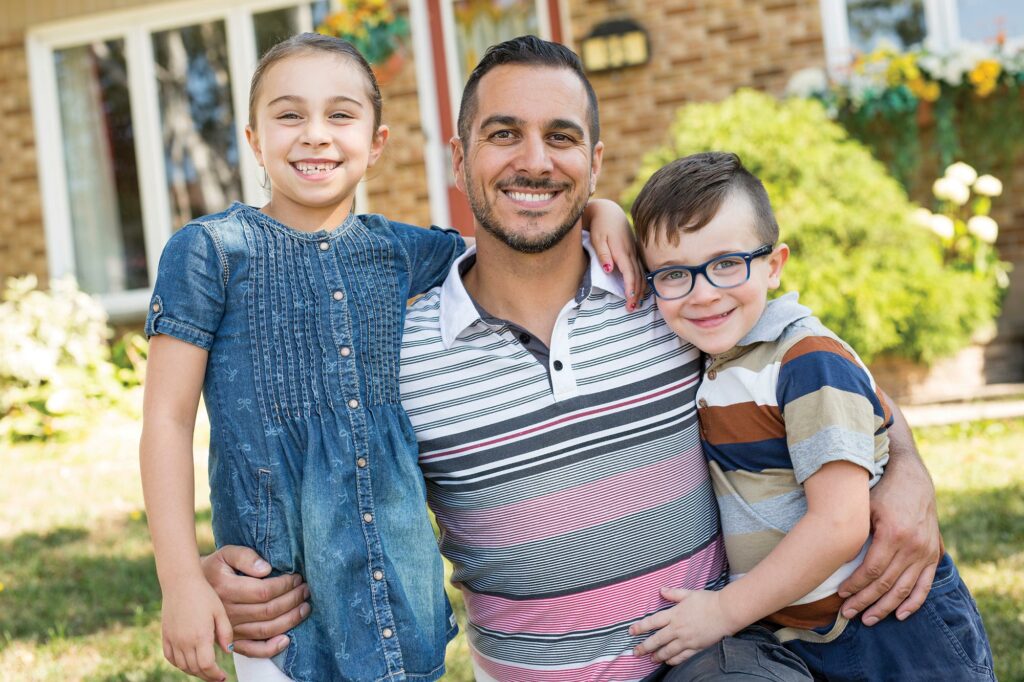 dad, son, and daughter in front of house